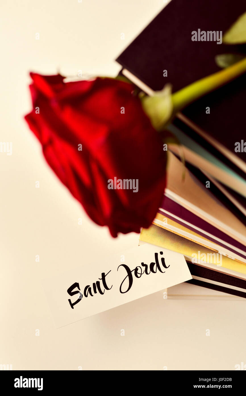 Une rose rouge sur une pile de livres et le texte Sant Jordi, le nom Catalan de Saint Georges 24, lorsqu'il est tradition de donner des roses rouges et de livres à Cat Banque D'Images