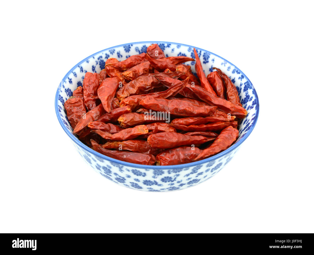 Birds Eye chilis dans un bol en porcelaine bleu et blanc avec un design floral, isolé sur fond blanc Banque D'Images
