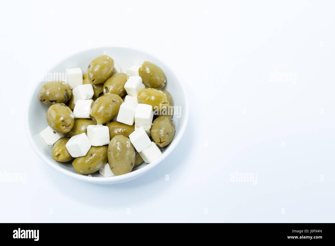 Très frais, olives, fromage blanc assaisonné et préparés en na bol blanc isolé en fond blanc Banque D'Images
