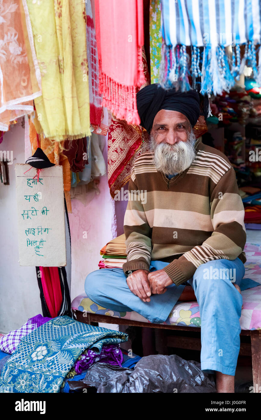 Homme sympathique commerçant Sikh barbu dans une boutique de tissus typiques portant turban, Pragpur, un village historique en Kagra district, Himachal Pradesh, Inde Banque D'Images