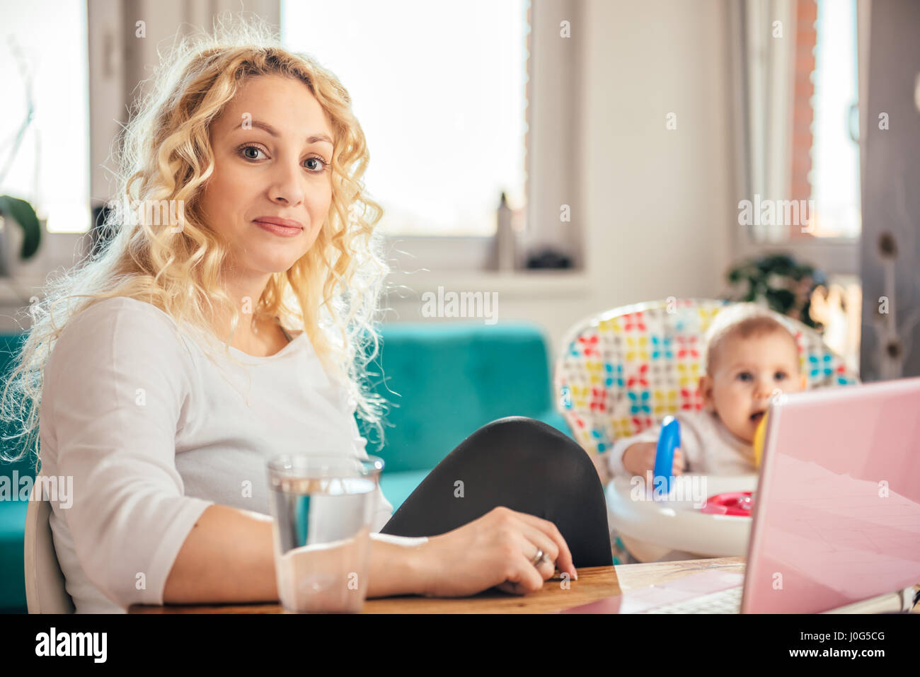 La mère et son bébé assis à un bureau pendant qu'elle travaille à l'ordinateur portable Banque D'Images