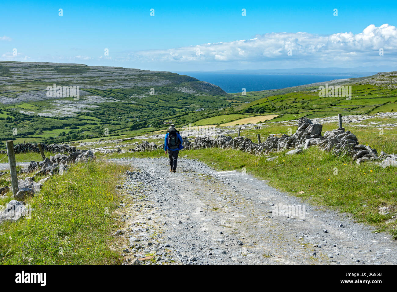 Un marcheur sur une piste de descendre dans la vallée de Caher, le Burren, comté de Clare, Irlande Banque D'Images