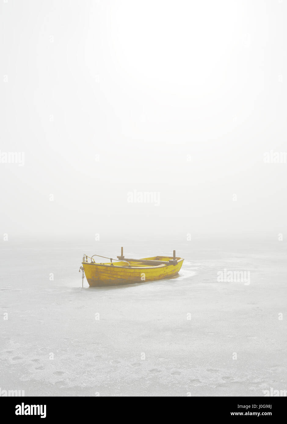 Bateau jaune piégés dans lac gelé en Matin brumeux Banque D'Images