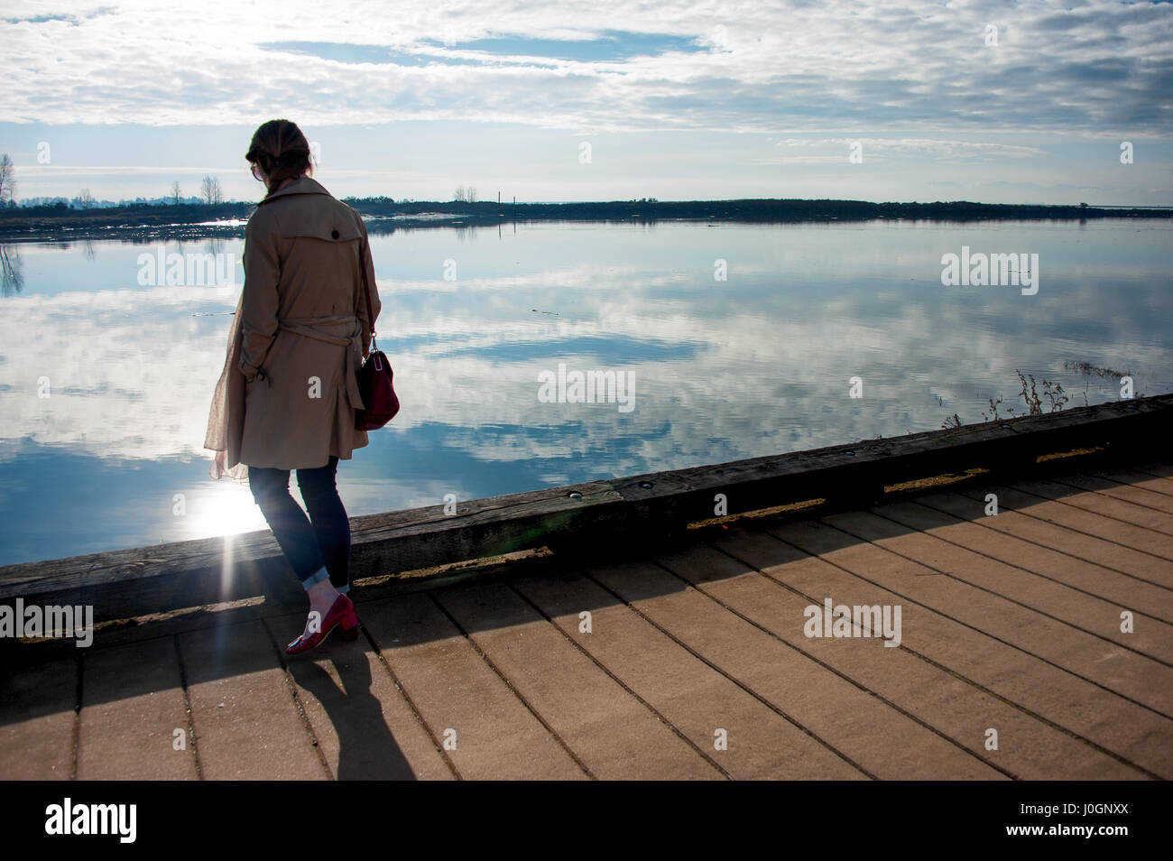 Figure féminine à côté de l'eau avec réflexion soleils Banque D'Images