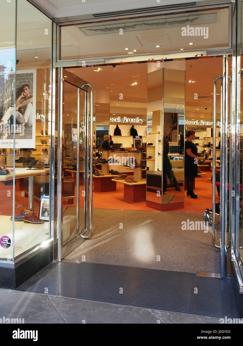 Entrée de la Russell et Bromley, magasin de chaussures dans le centre de Manchester, montrant la porte et l'intérieur avec un membre féminin du personnel. Banque D'Images