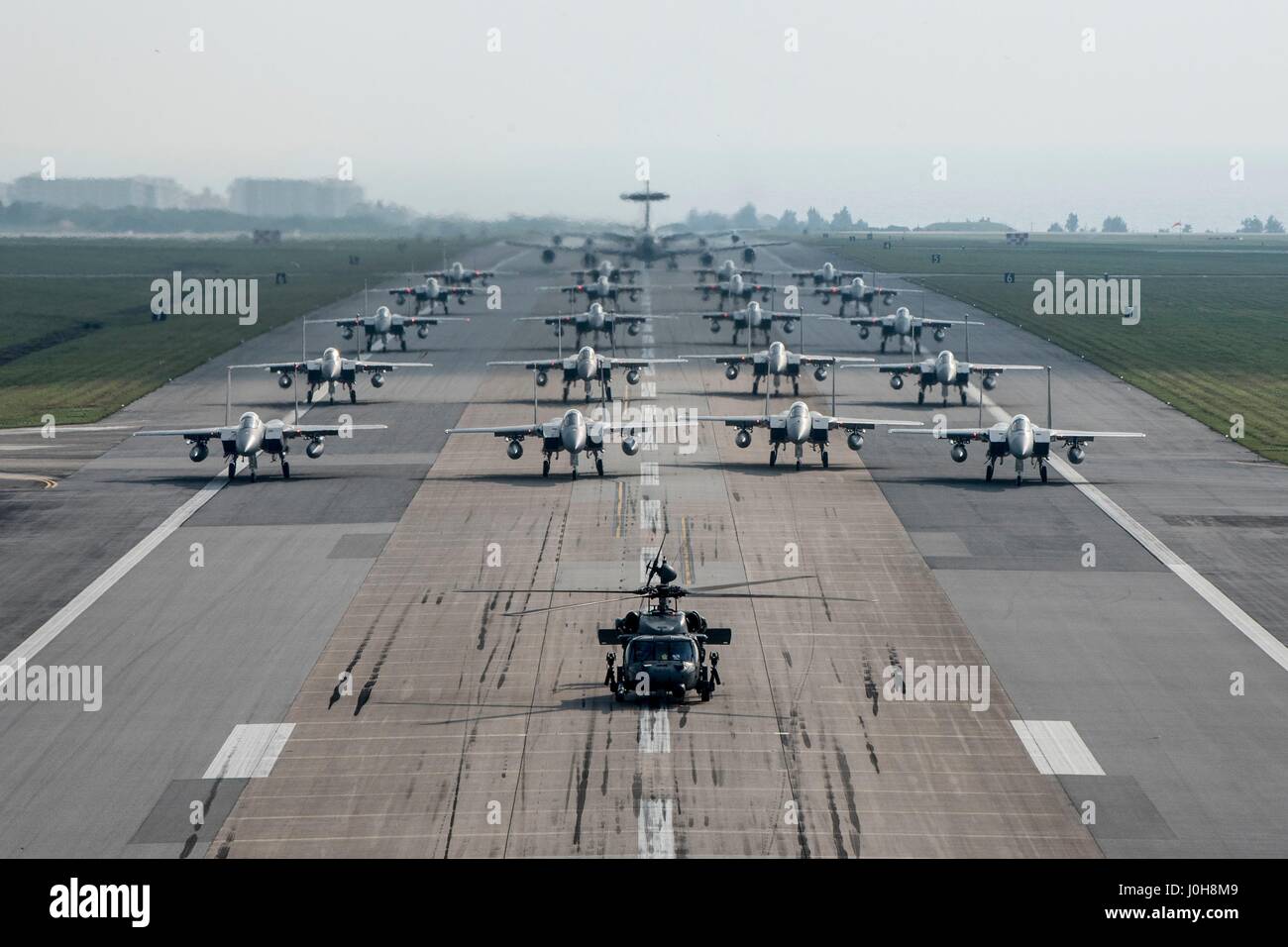 U.S. Air Force 18e Escadre des taxis sur la piste avec HH-60 Pave prêt au combat des faucons, des F-15 Eagle, E-3 sentinelles et KC-135 Stratotankers pendant un éléphant à pied dans le cadre d'un exercice sans préavis à Kadena Air Base le 12 avril 2017 au Japon, Kadena. L'exercice est la preuve de la capacité de générer rapidement la lutte contre la puissance aérienne dans le cas d'une attaque que les tensions augmentent avec la Corée du Nord. Banque D'Images