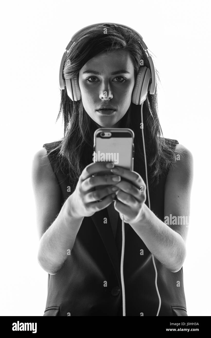 Photo en noir et blanc de l'élégante jeune femme dans les écouteurs using smartphone Banque D'Images