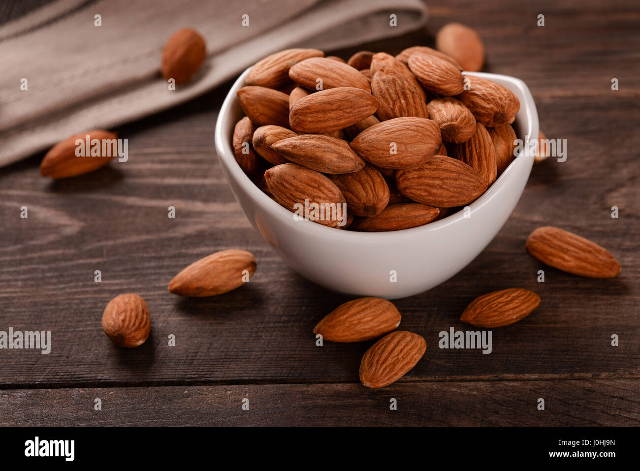 Bol en céramique d'amandes dans le fond en bois sombre. Banque D'Images