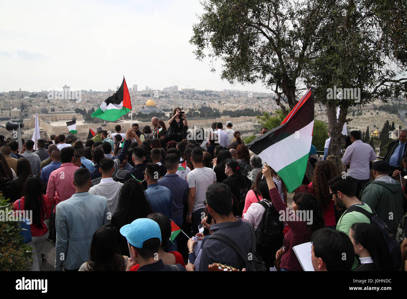 Les chrétiens palestiniens assister à une procession des Rameaux sur le mont oliviers tenant des drapeaux palestiniens voir le Dôme du rocher sur le mont du Temple de l'avant Banque D'Images
