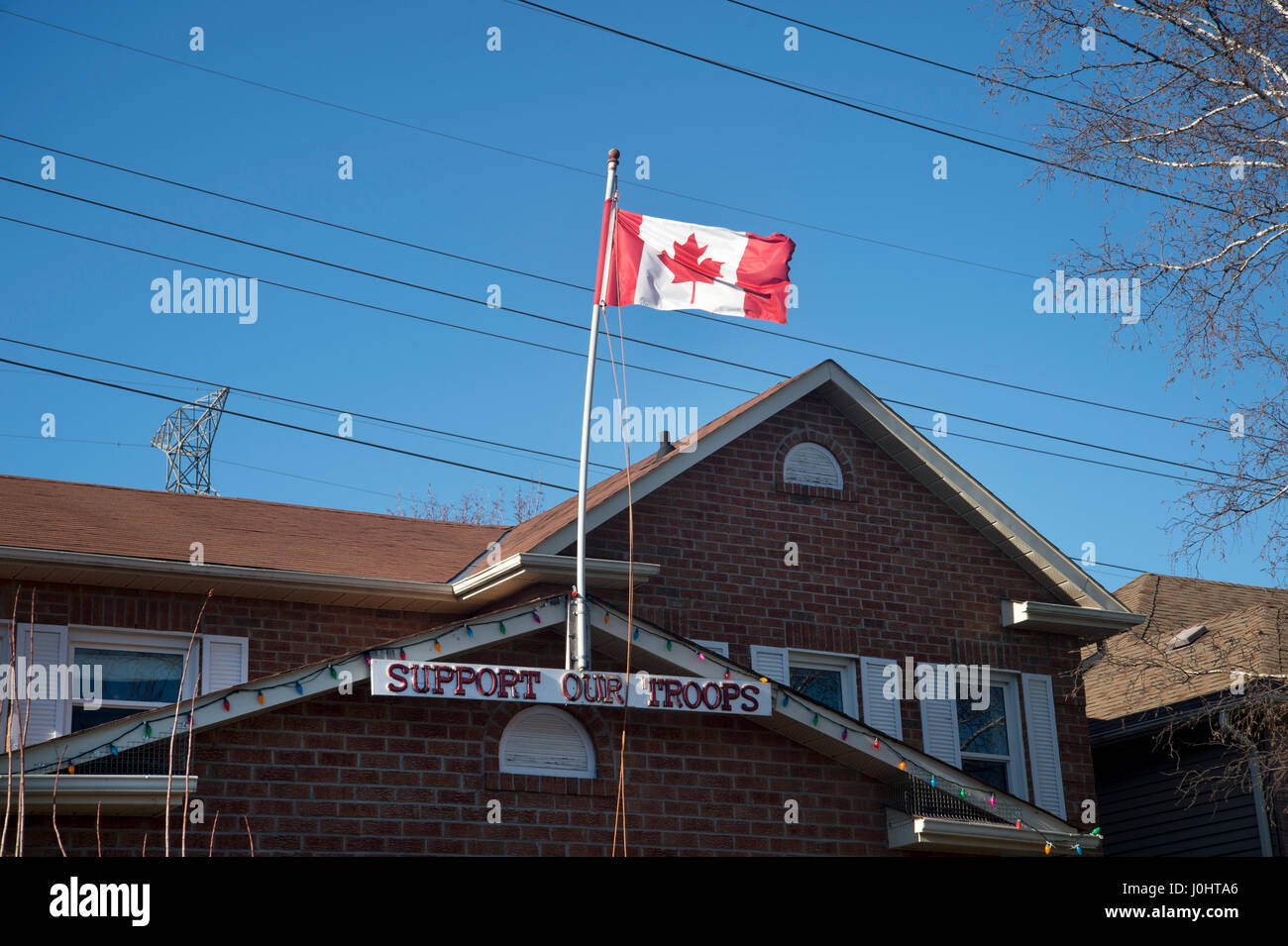 Pickering, Ontario, Canada. Une maison familiale avec un panneau disant 'appui de nos troupes et battant pavillon canadien, une feuille d'érable rouge sur blanc Banque D'Images