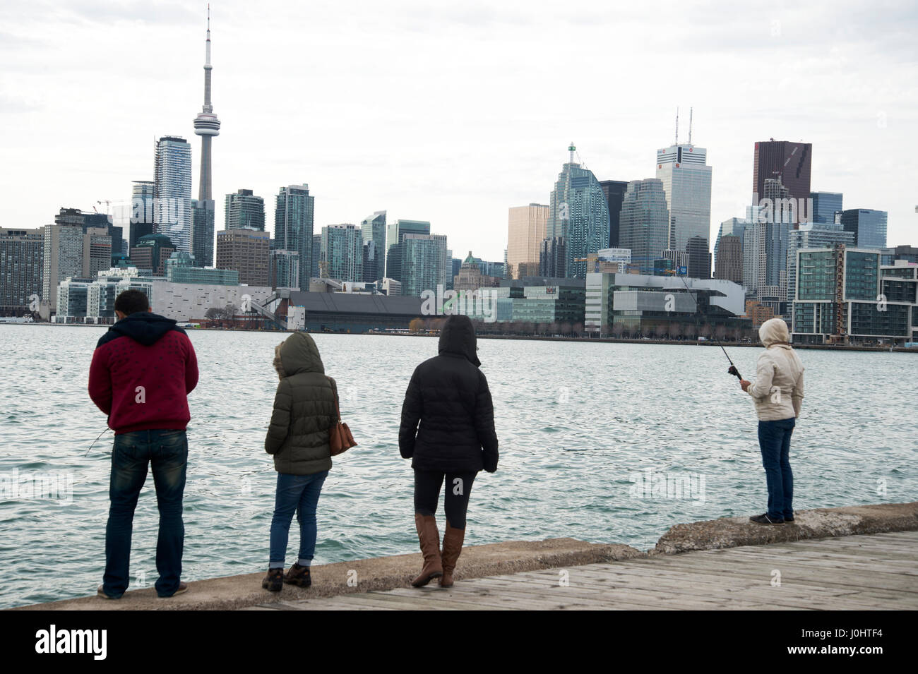 Canada, Toronto. La ville et le bord de l'eau avec un groupe de jeunes à la pêche. Banque D'Images