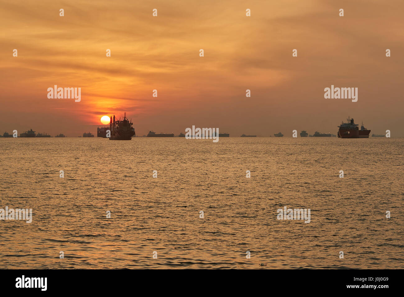 Le lever du soleil sur les navires à l'ancre dans le détroit de Singapour. Banque D'Images