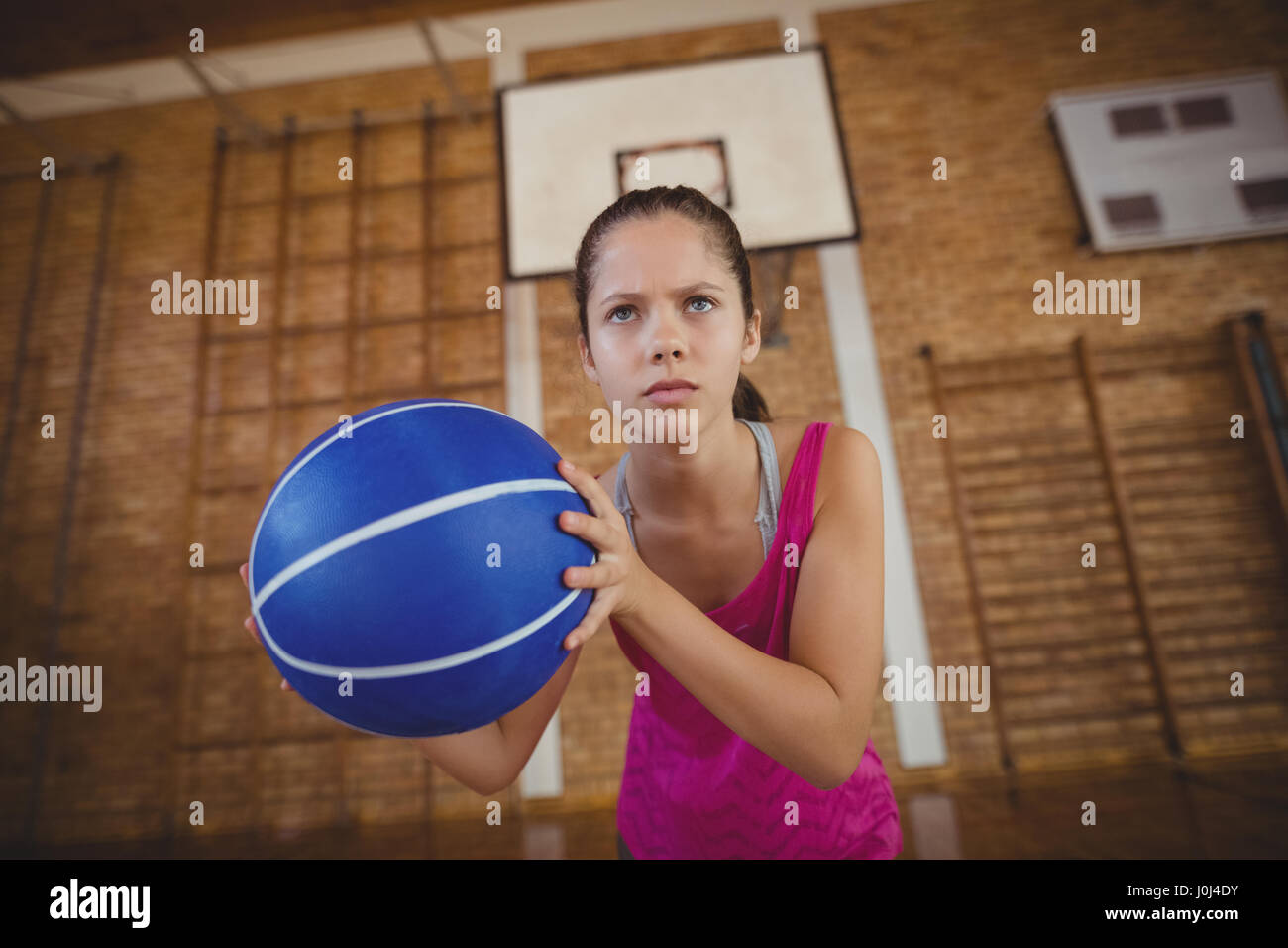 Déterminé lycéenne jouant au basket-ball dans la cour Banque D'Images