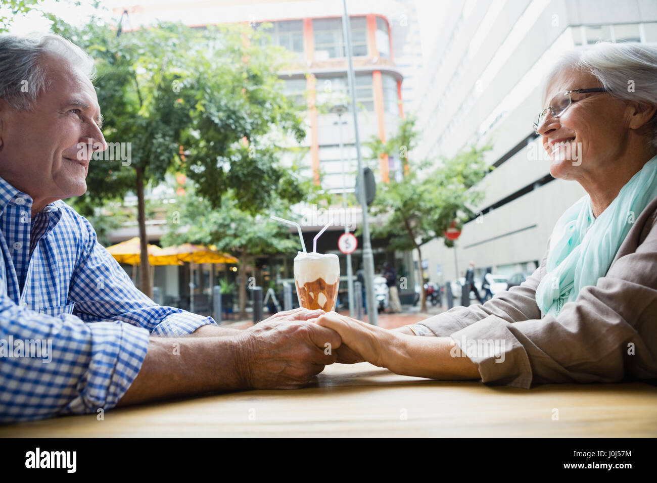 Romantic senior couple holding hands in outdoor cafÃƒÂ© Banque D'Images