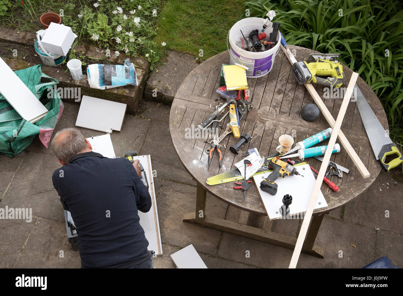 Une vue d'un homme engagé dans des travaux de bricolage sur le patio du jardin Banque D'Images