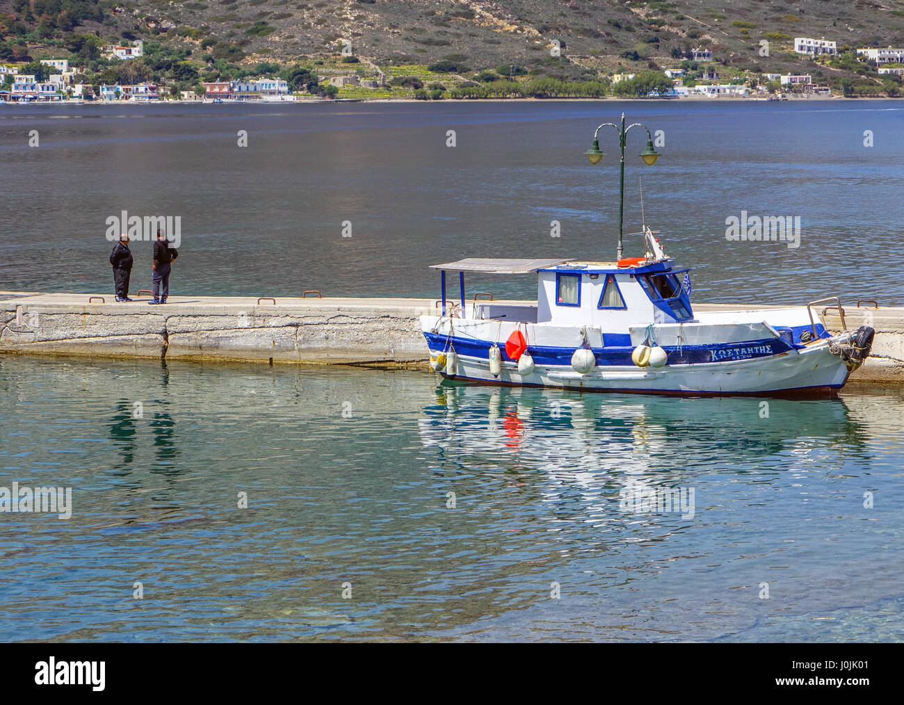 En bois blanc et bleu bateau taxi en attente à Myrties jerry avec deux personnes en noir Banque D'Images
