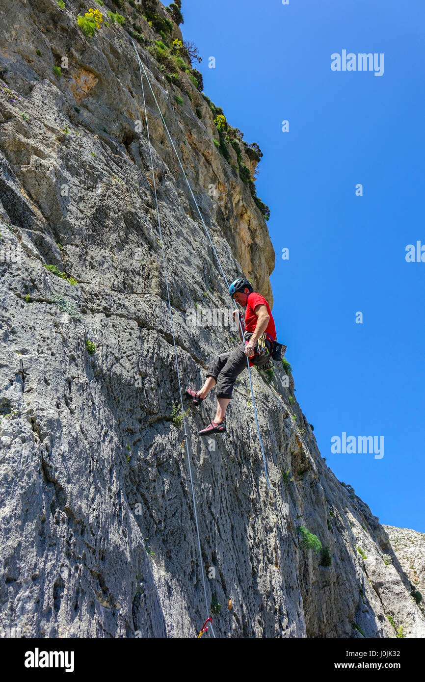 Rock climber en rouge, avec casque, corde de Kalymnos, Grèce, Banque D'Images