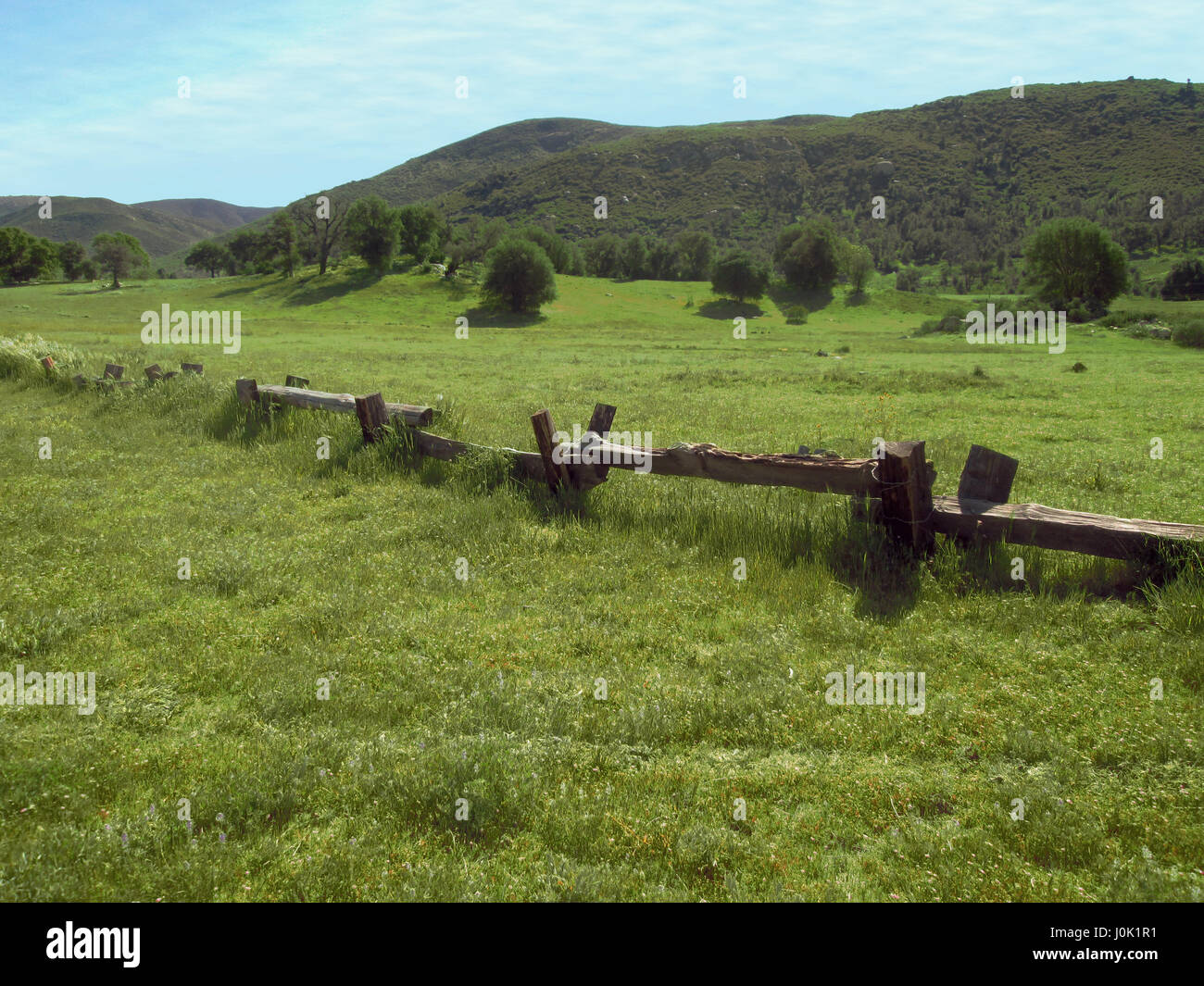 Un champ d'herbe verte et collines en arrière-plan avec une balustrade en bois clôture rustique. Banque D'Images