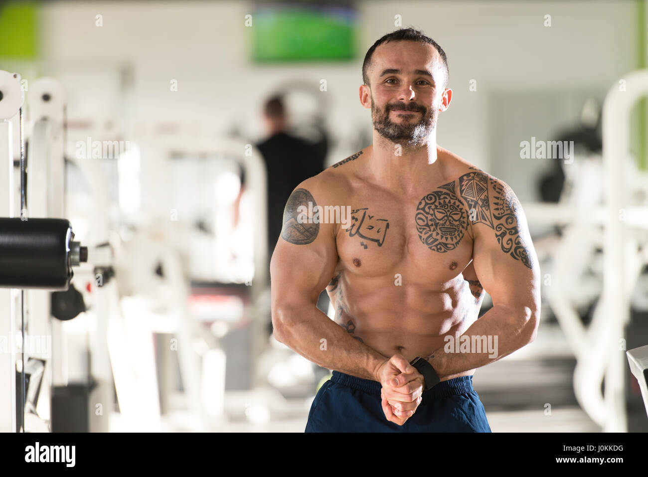 Jeune homme sain Tatouage Soyons forts dans la salle de sport et Flexing Muscles musculaire