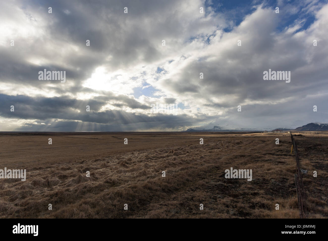 Les rayons du soleil percent les nuages, frapper le golden champs dans la vallée ci-dessous. La péninsule de snæfellsnes (Glasgow), dans l'ouest de l'Islande Banque D'Images