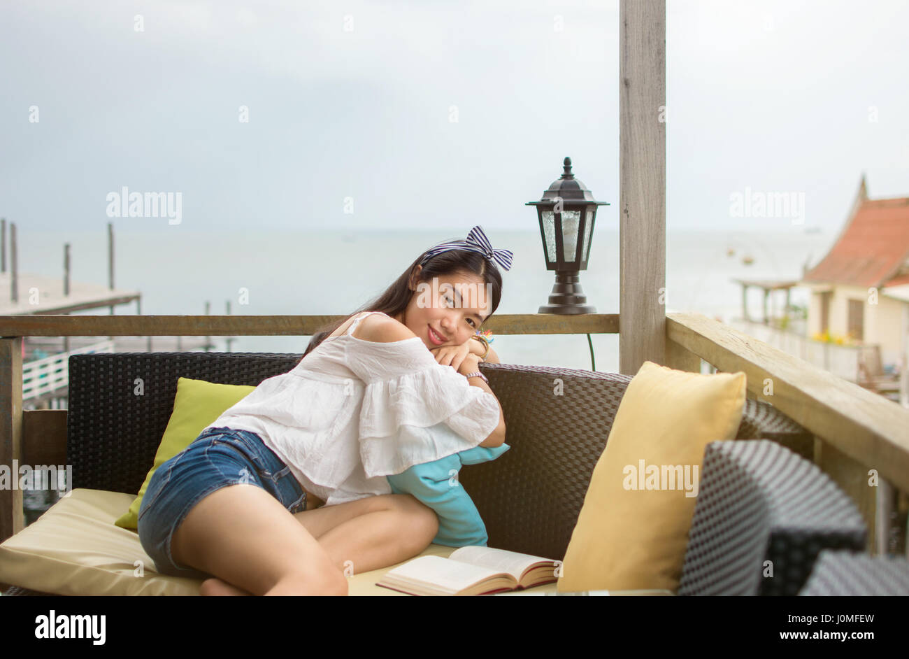 Jeune fille lisant un livre sur le balcon avec vue sur la mer Banque D'Images