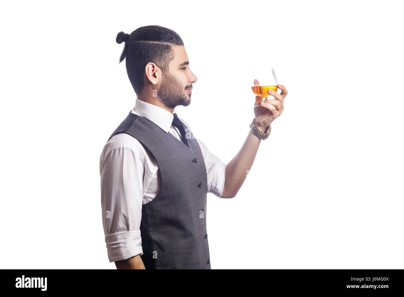 Beau bearded businessman holding a glass of whiskey. Vue de côté. à la recherche de verre et souriant, studio shot, isolé sur fond blanc. Banque D'Images