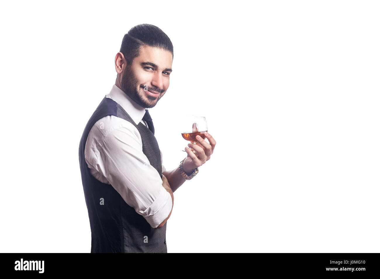 Beau bearded businessman holding a glass of whiskey. holding glass and looking at camera avec sourire. studio shot, isolé sur fond blanc. Banque D'Images