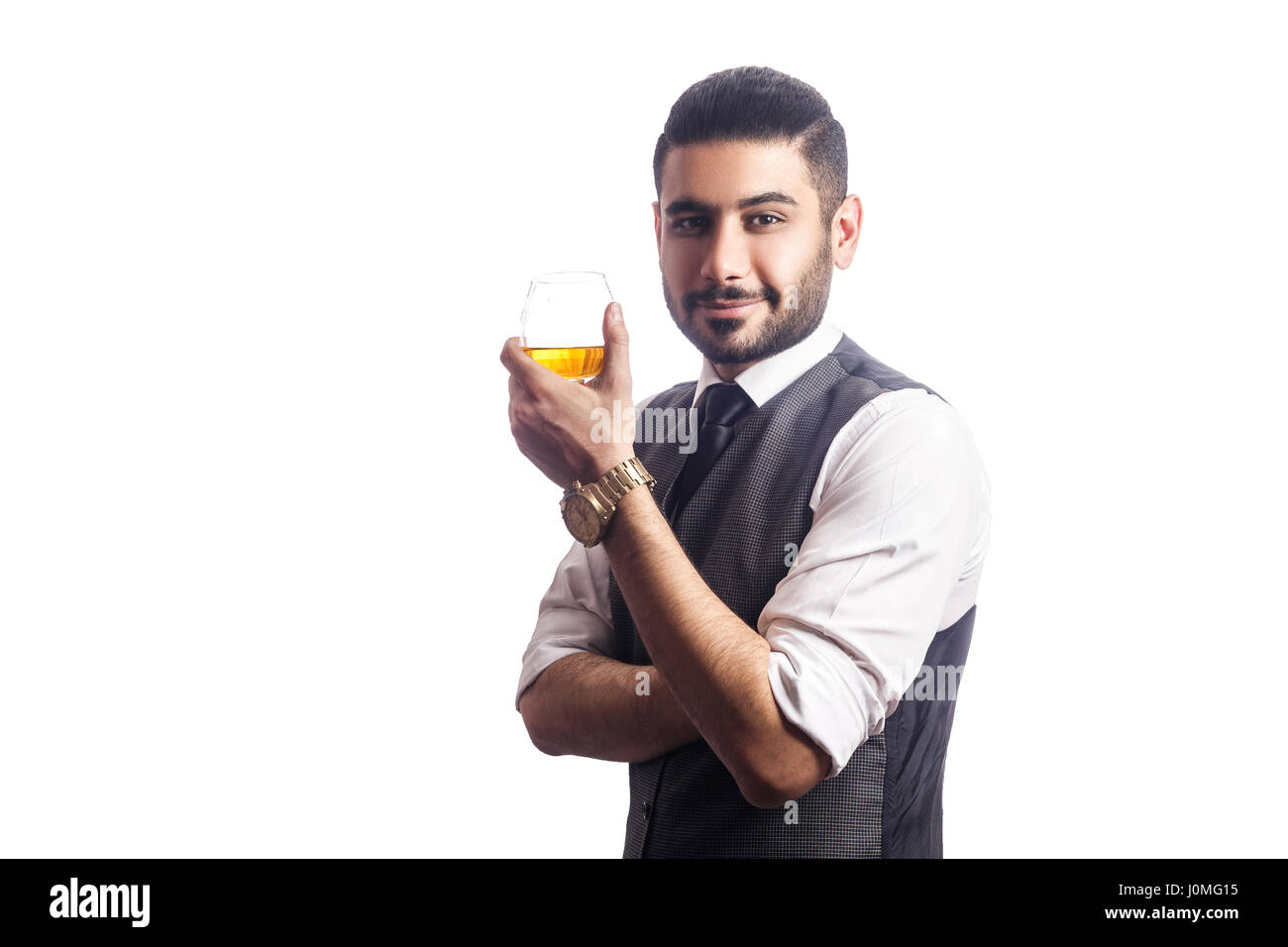 Beau bearded businessman holding a glass of whiskey. holding glass, smiling and looking at camera. studio shot, isolé sur fond blanc. Banque D'Images