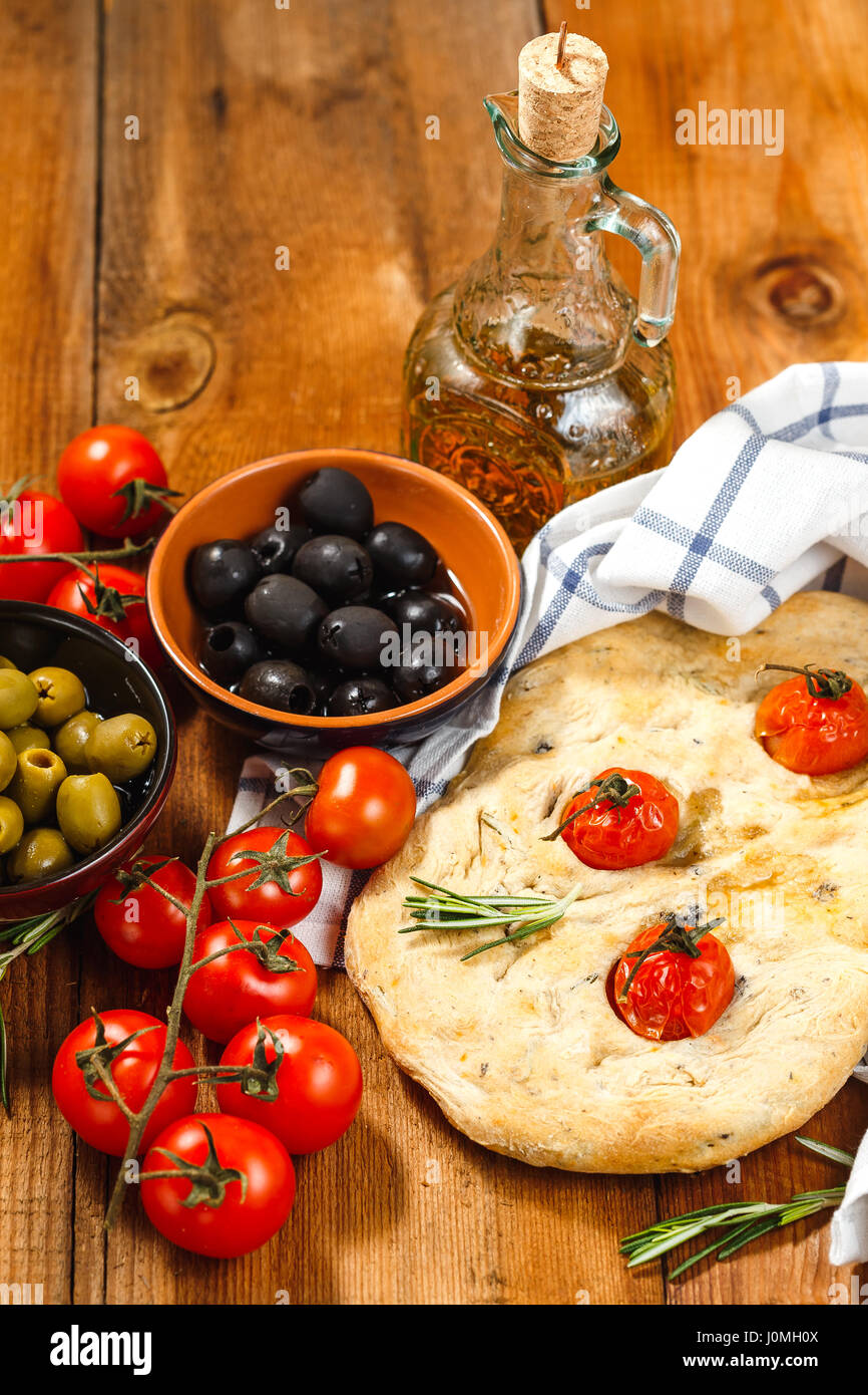 Focaccia italienne traditionnelle avec les tomates et le romarin avec de l'huile d'olive sur la table en bois Banque D'Images