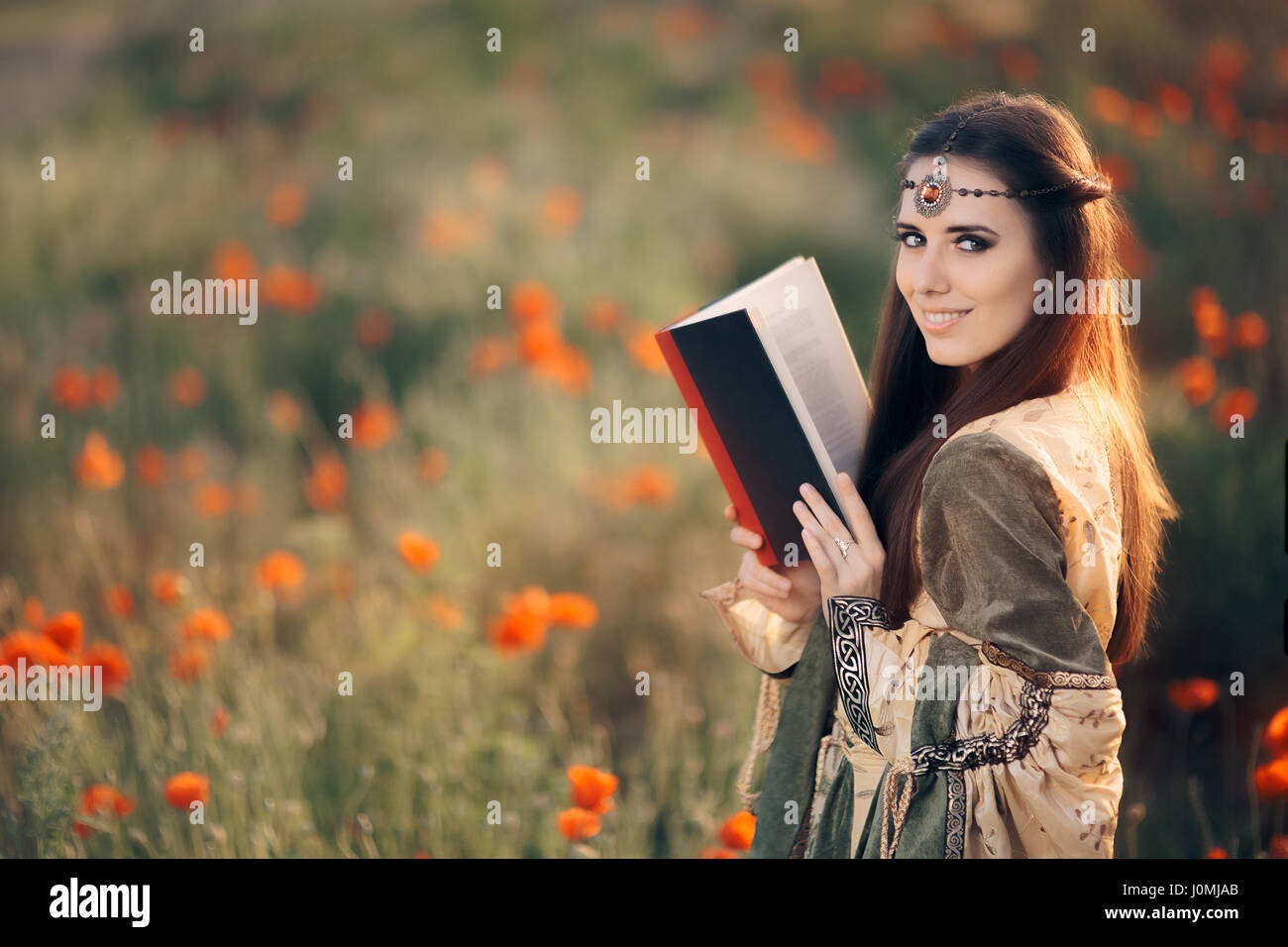 Cité médiévale de la lecture d'un livre magique dans un champ de coquelicots Banque D'Images