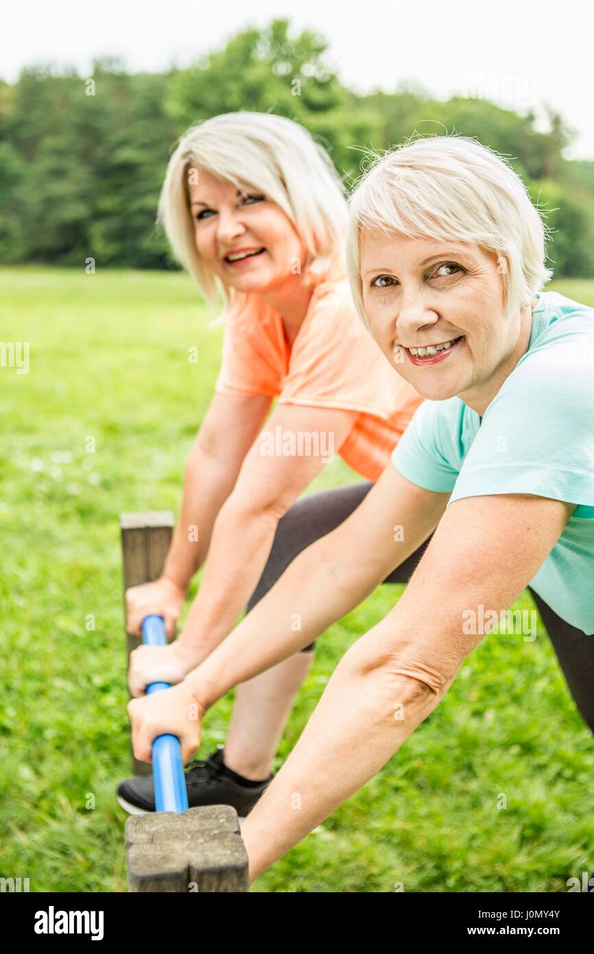 Deux femmes smiling towards camera holding railing. Banque D'Images