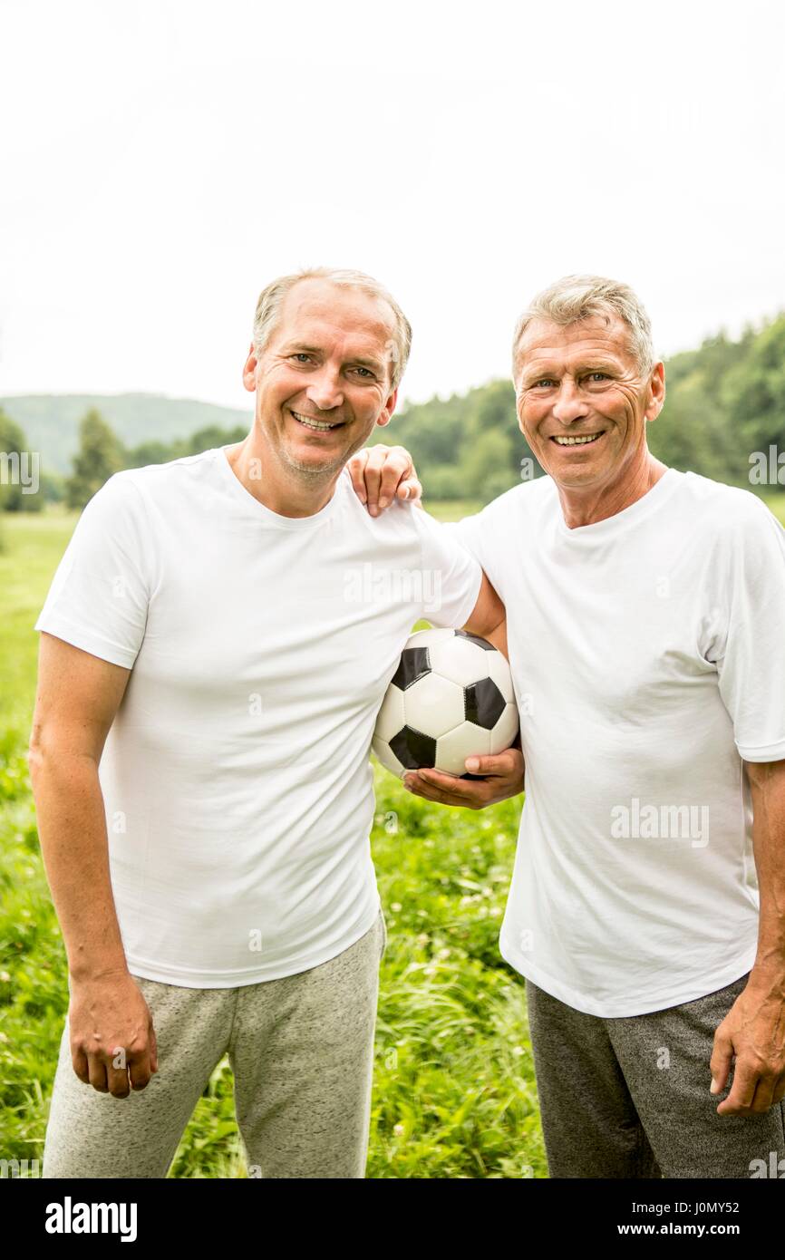 Deux hommes en armes autour de l'autre tenant le football. Banque D'Images