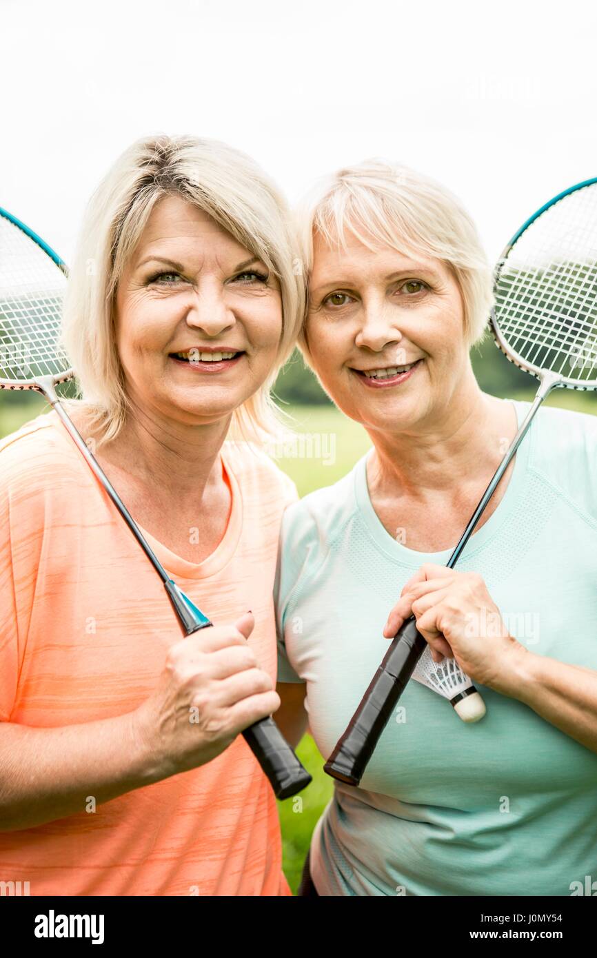 Deux femmes occupent des raquettes de badminton, en souriant. Banque D'Images