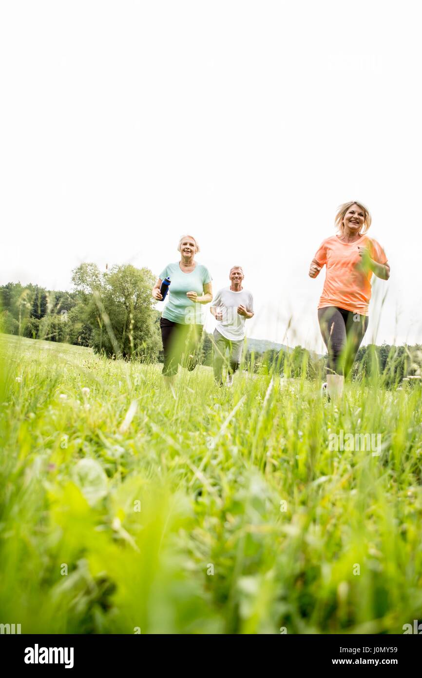 Trois personnes s'exécutant en champ. Banque D'Images