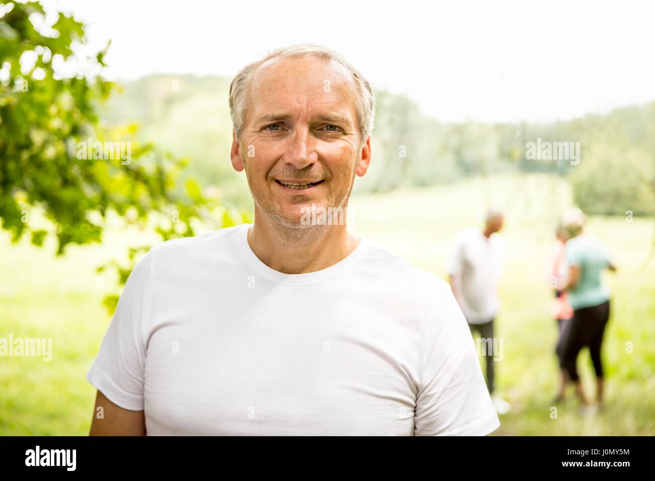 Man wearing white t-shirt sourire vers la caméra. Banque D'Images
