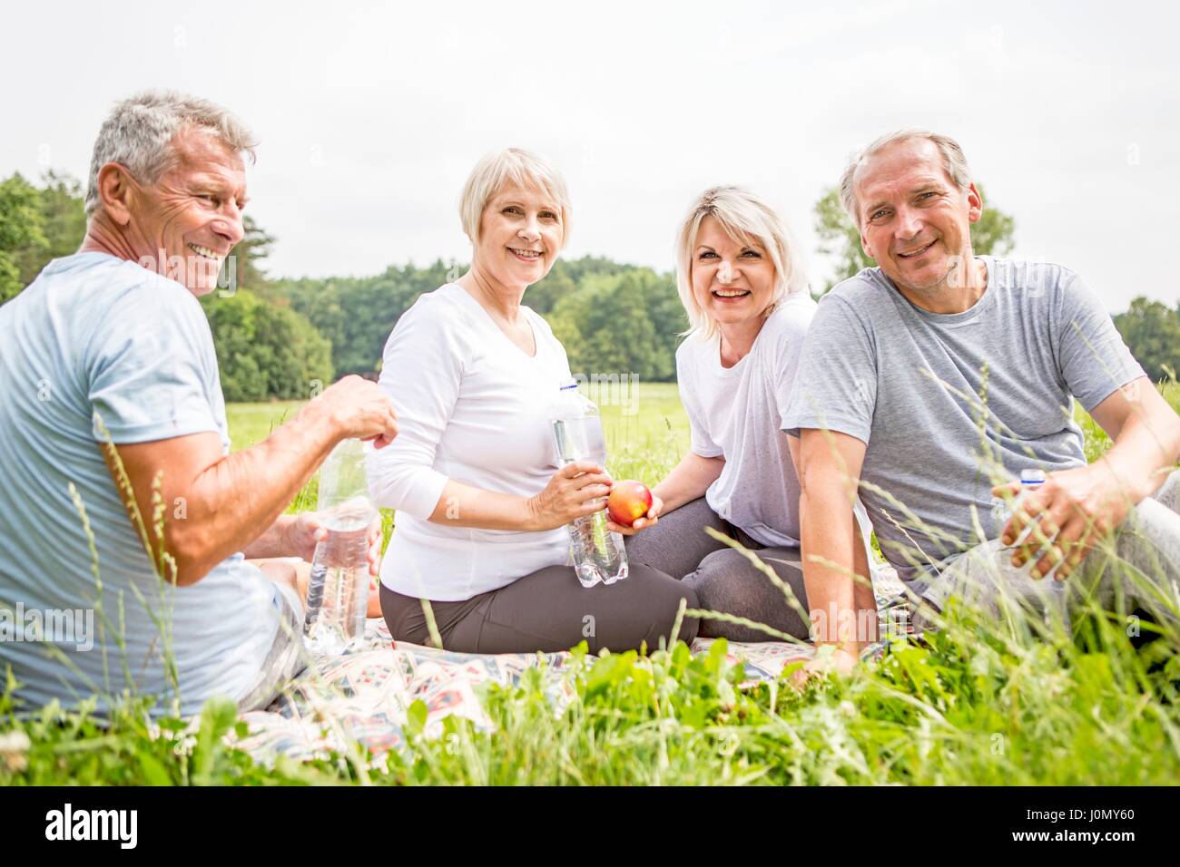 Quatre personnes assises sur l'herbe avec de l'eau. Banque D'Images