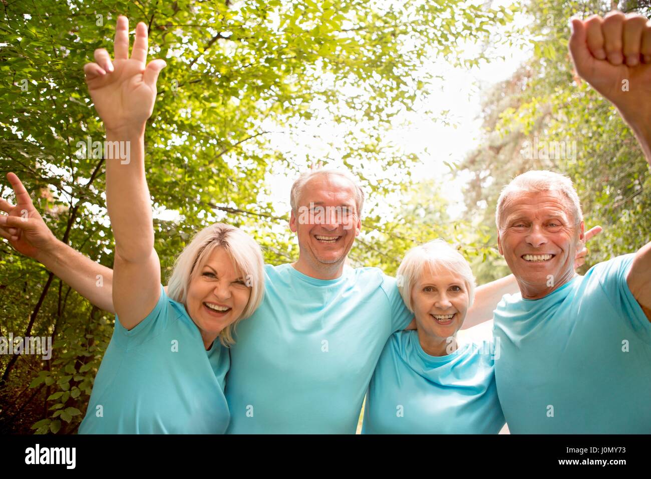 Quatre personnes en bleu t-shirts, souriant et acclamer. Banque D'Images