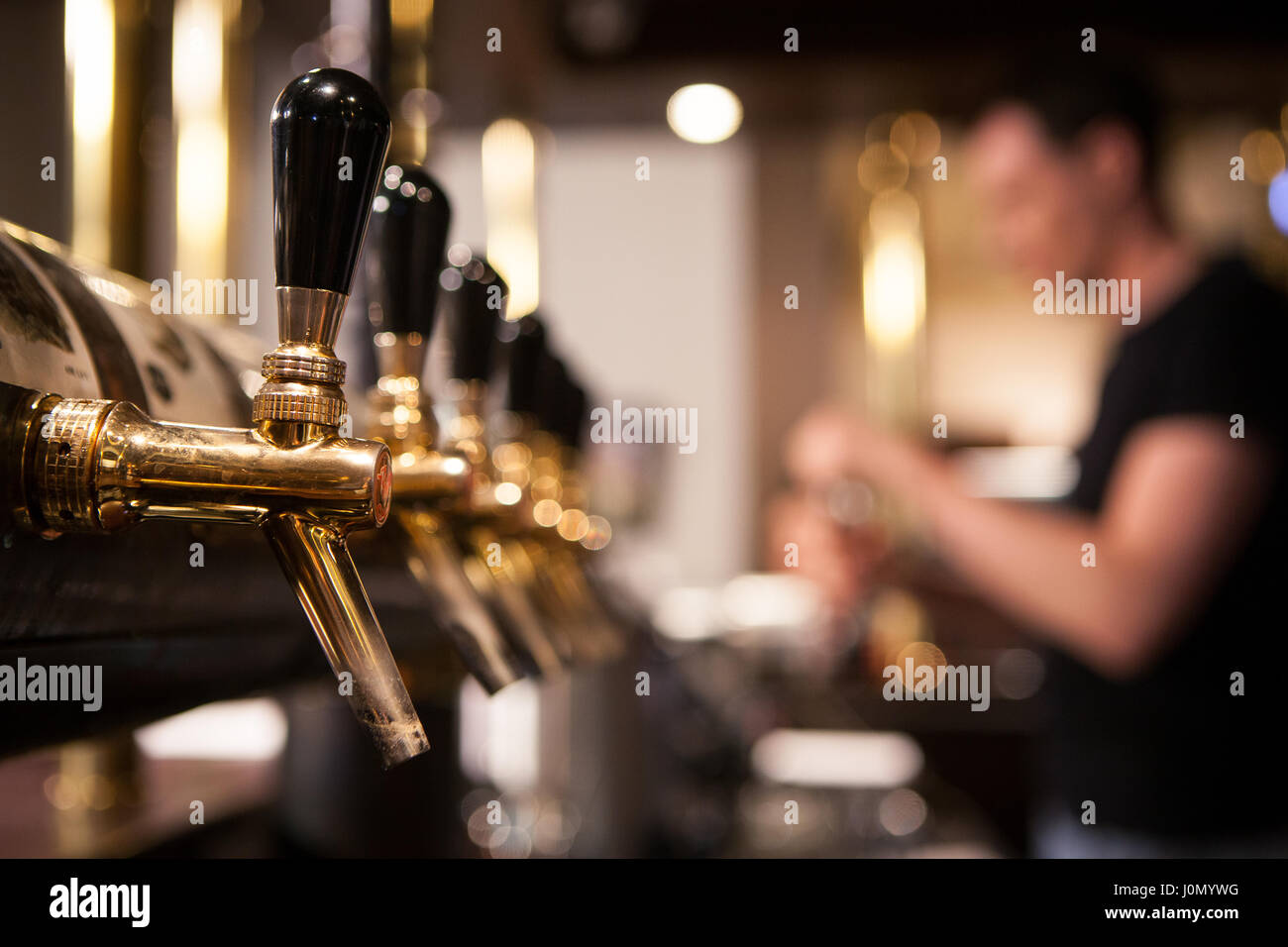 Beaucoup de vintage Golden les poignées de bière dans le bar avec le barman en arrière-plan Banque D'Images