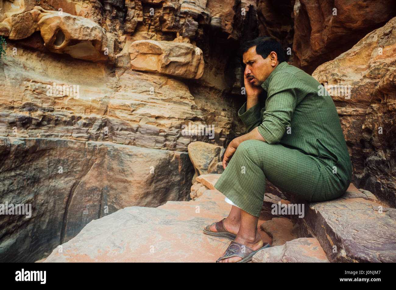 Guide expert mousseline de parler au téléphone à l'intérieur d'une formation de roches anciennes. Le désert de Wadi Rum. La Jordanie. Banque D'Images