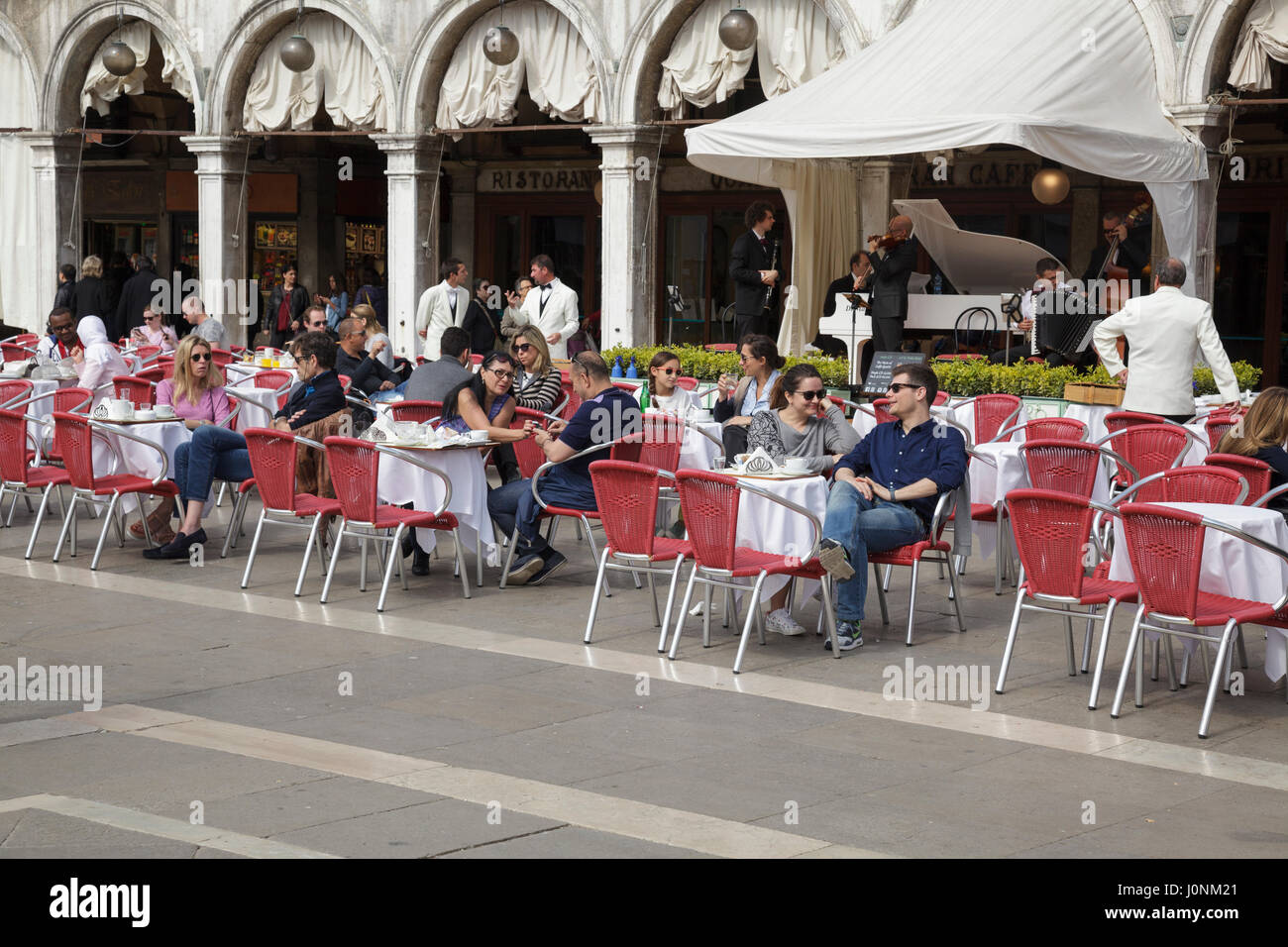 Les touristes s'asseoir à cafés en plein air à la place Saint Marc, Venise, Vénétie, Italie Banque D'Images
