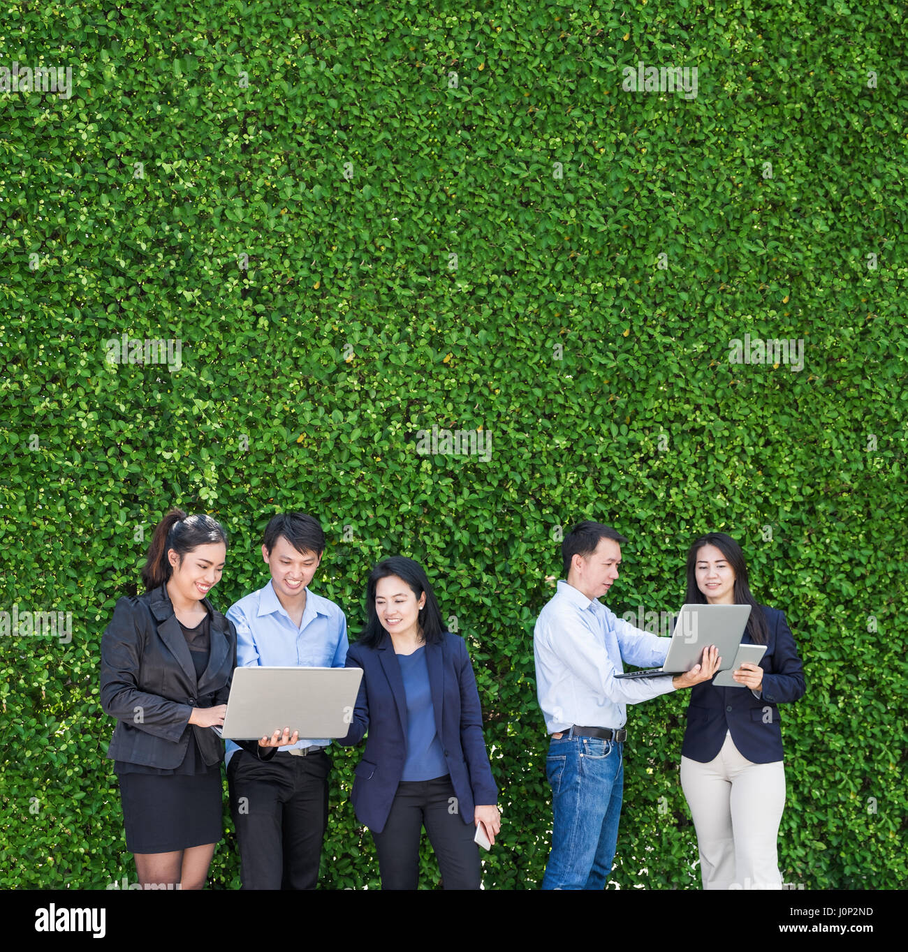 Young travaillant à l'extérieur du bureau à l'aide d'un ordinateur portable téléphone mobile et tablette à feuille verte,mur,concept mobile office cop Banque D'Images
