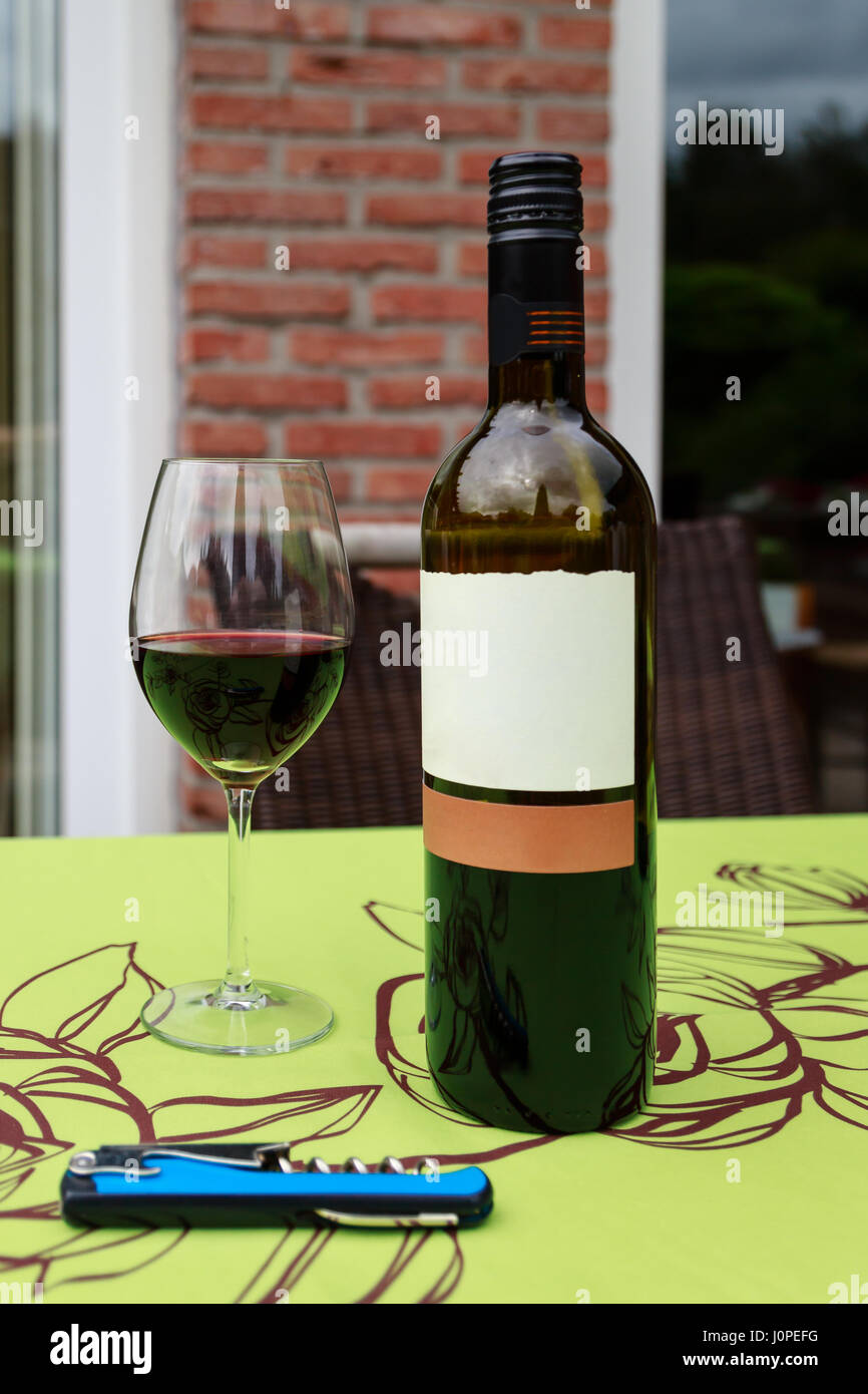 Un verre et une bouteille de vin rouge sur une table d'extérieur Banque D'Images