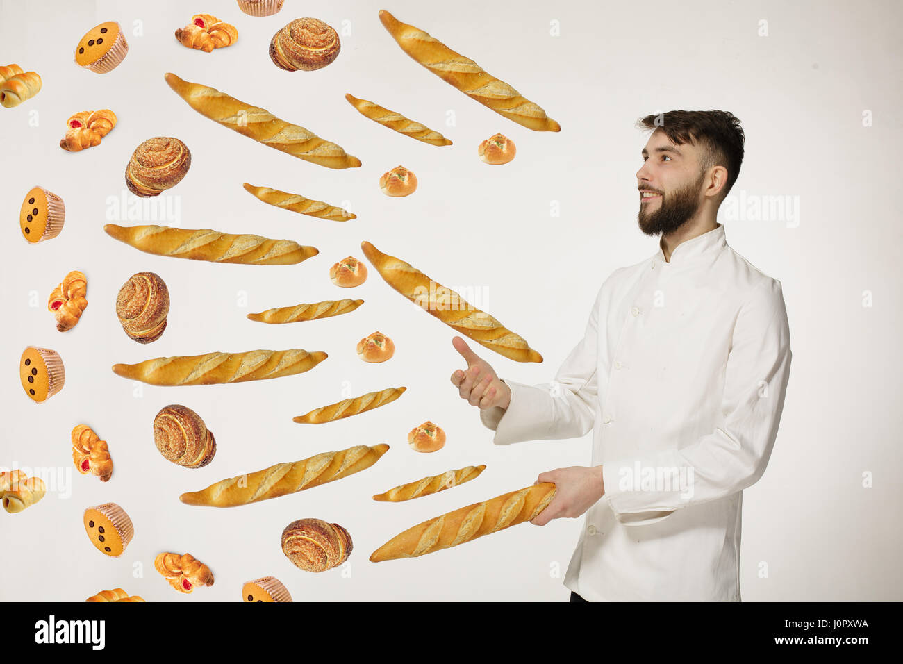 Beau rire baker jeter la baguette en l'air sur fond blanc. Banque D'Images