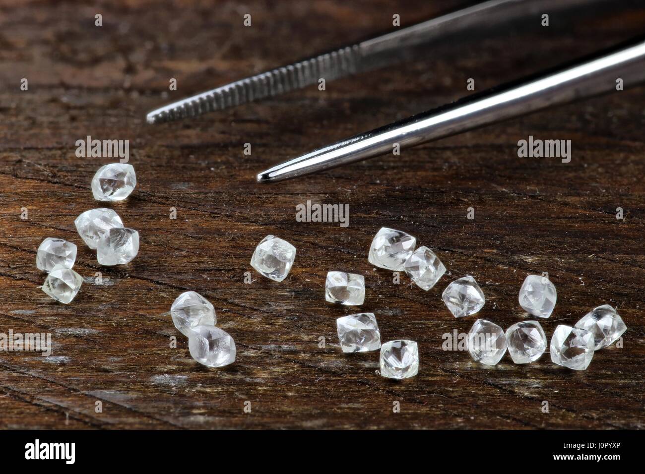 Les diamants bruts avec des pincettes sur fond de bois Banque D'Images