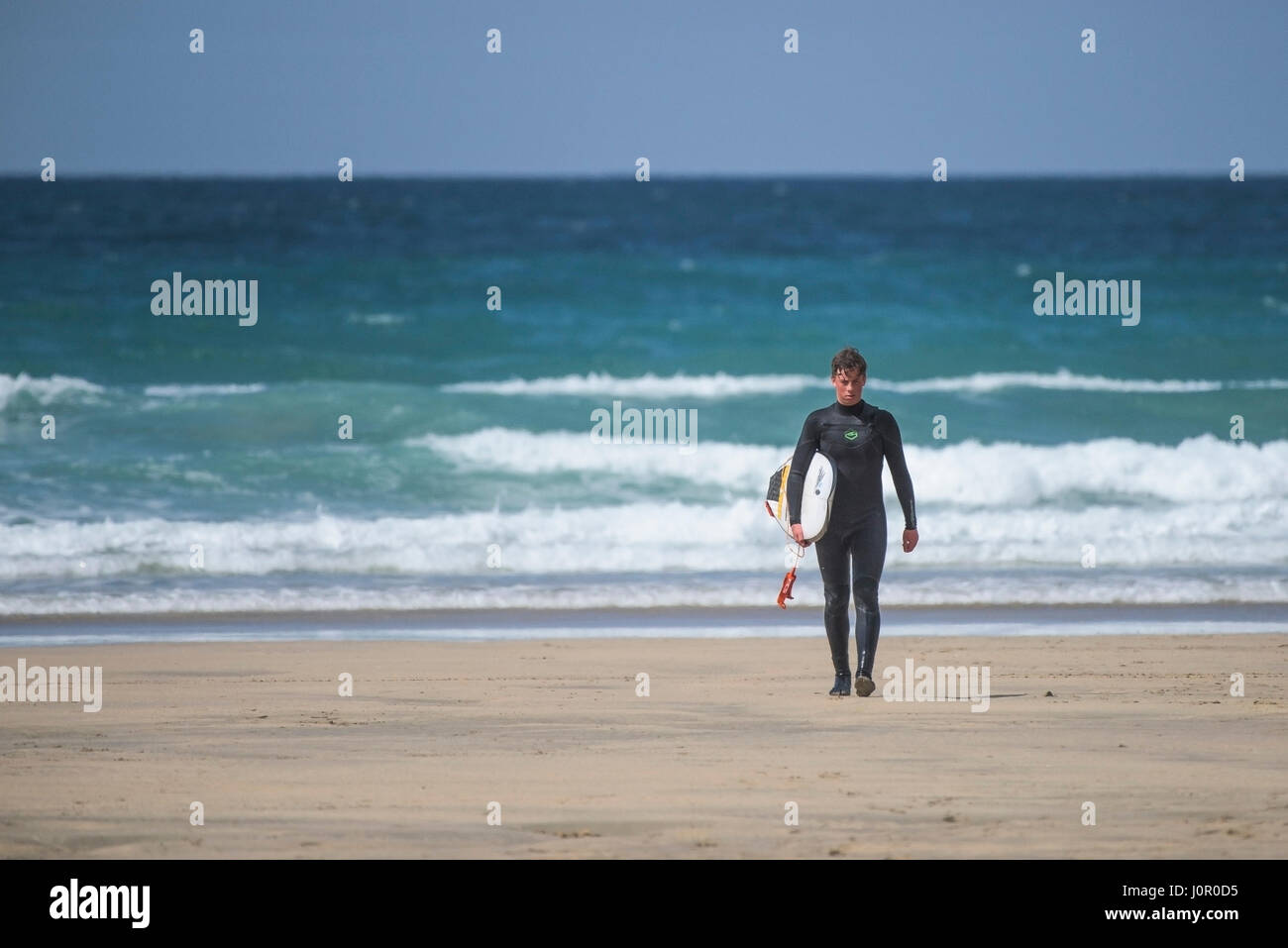 Newquay Fistral Surfer en laissant la mer autour de la mer, l'exécution de surf surf Wetsuit Watersport tourisme balnéaire Beach Appartement De Vacances Banque D'Images