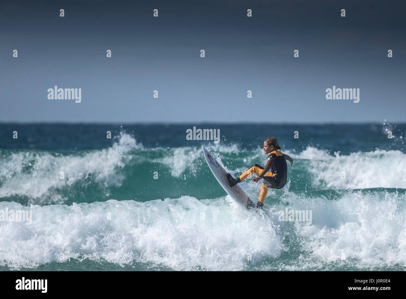 UK Surf ; un jeune surfer une vague. Enfant surf wave. Banque D'Images