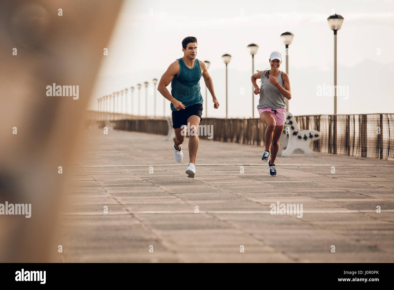 Couple de coureurs sprintant le long de la route par la mer. Couple de remise en forme d'exécution sur la promenade de bord de mer. Banque D'Images