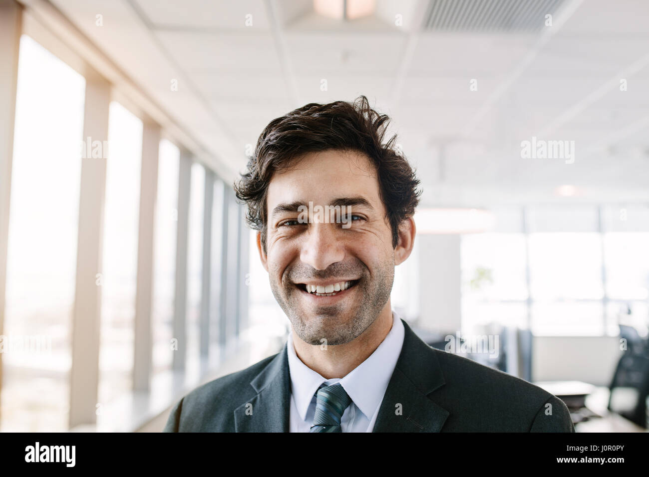 Portrait de jeunes businessman standing in office. Manager en fonction de recherche à l'appareil photo avec un sourire. Banque D'Images