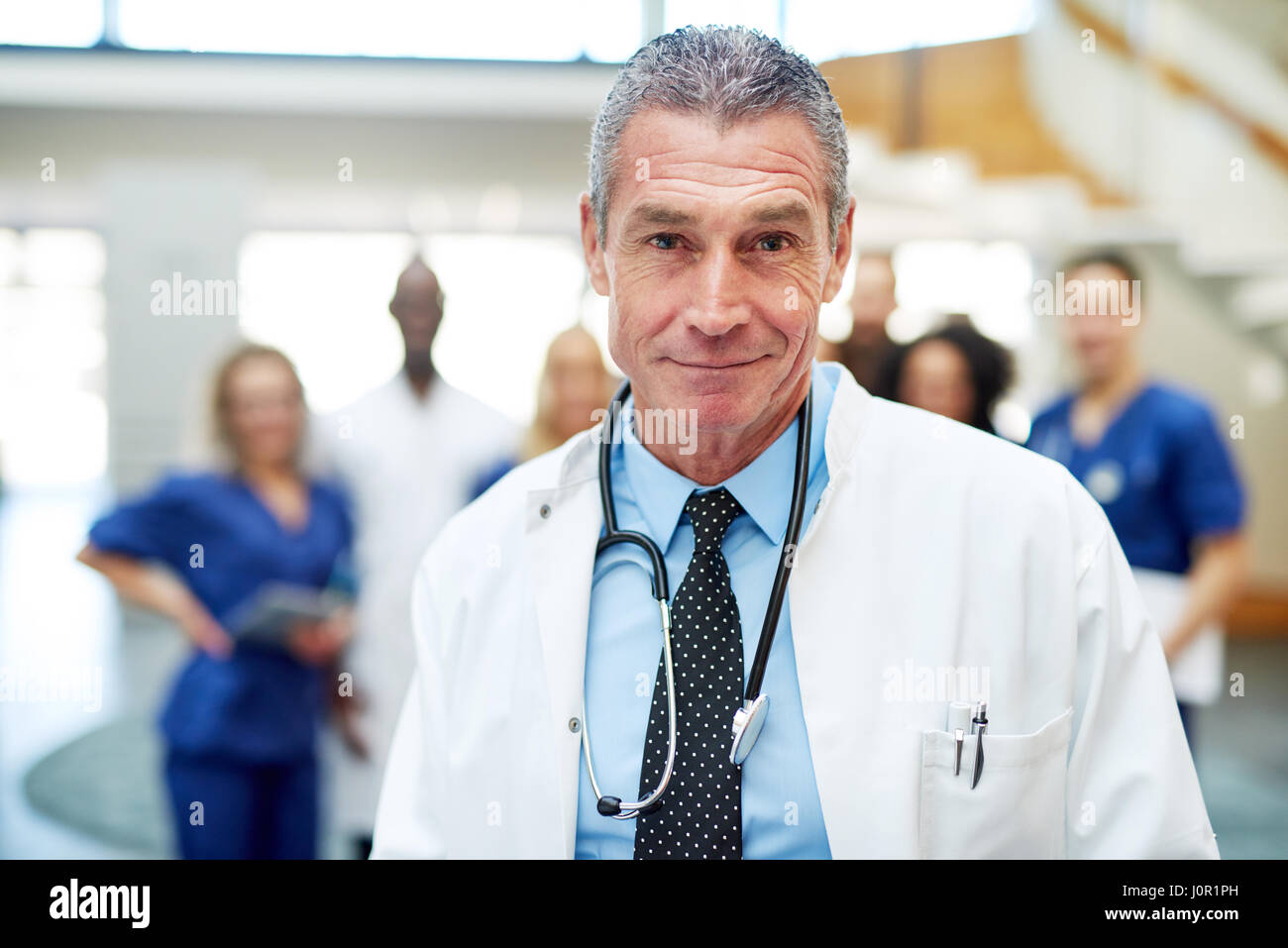 Portrait of doctor looking at camera adultes debout avec l'équipe dans une clinique. Banque D'Images
