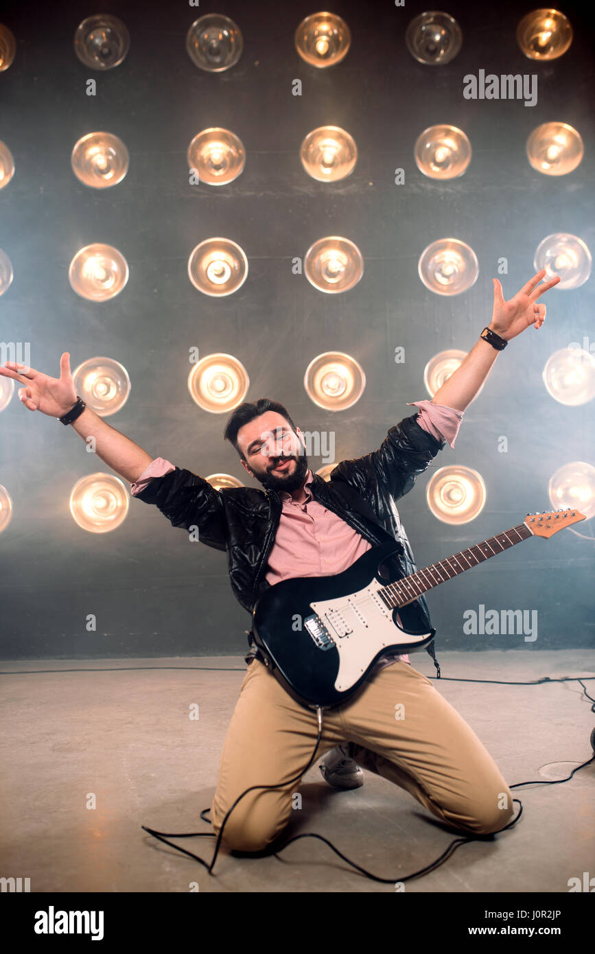 Homme de spectacle avec la guitare sur la scène avec les décors de lumières. Music Entertainment Banque D'Images